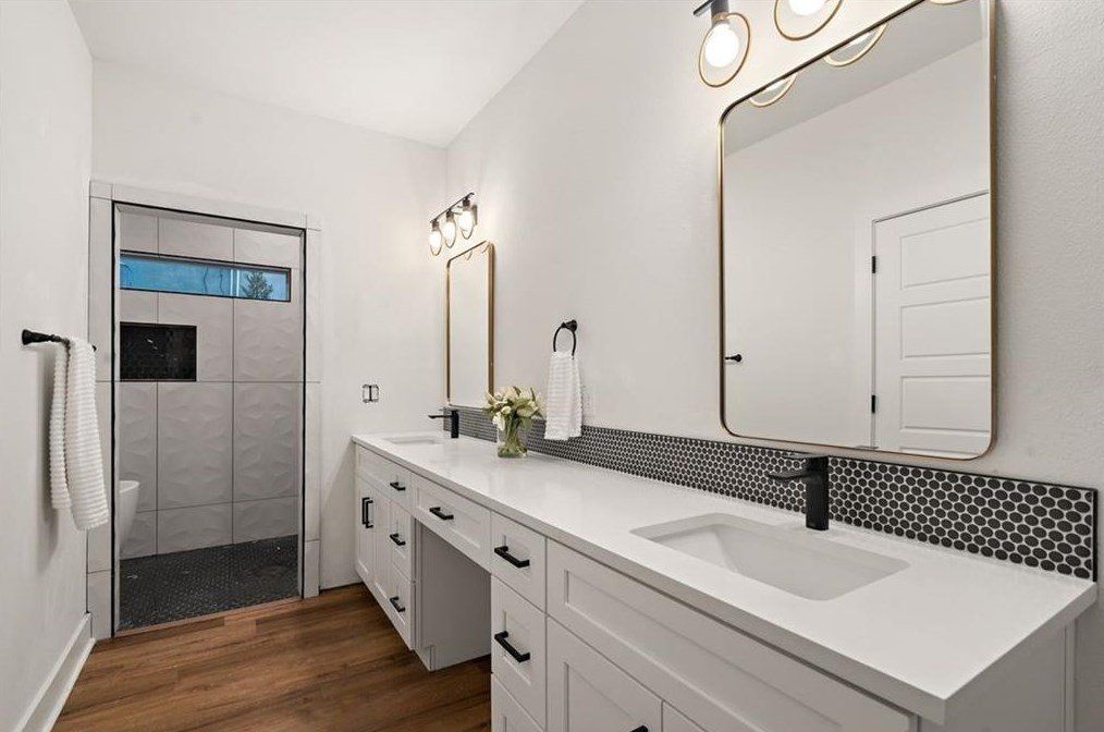 Modern bathroom with white cabinets, two sinks, and a walk-in shower