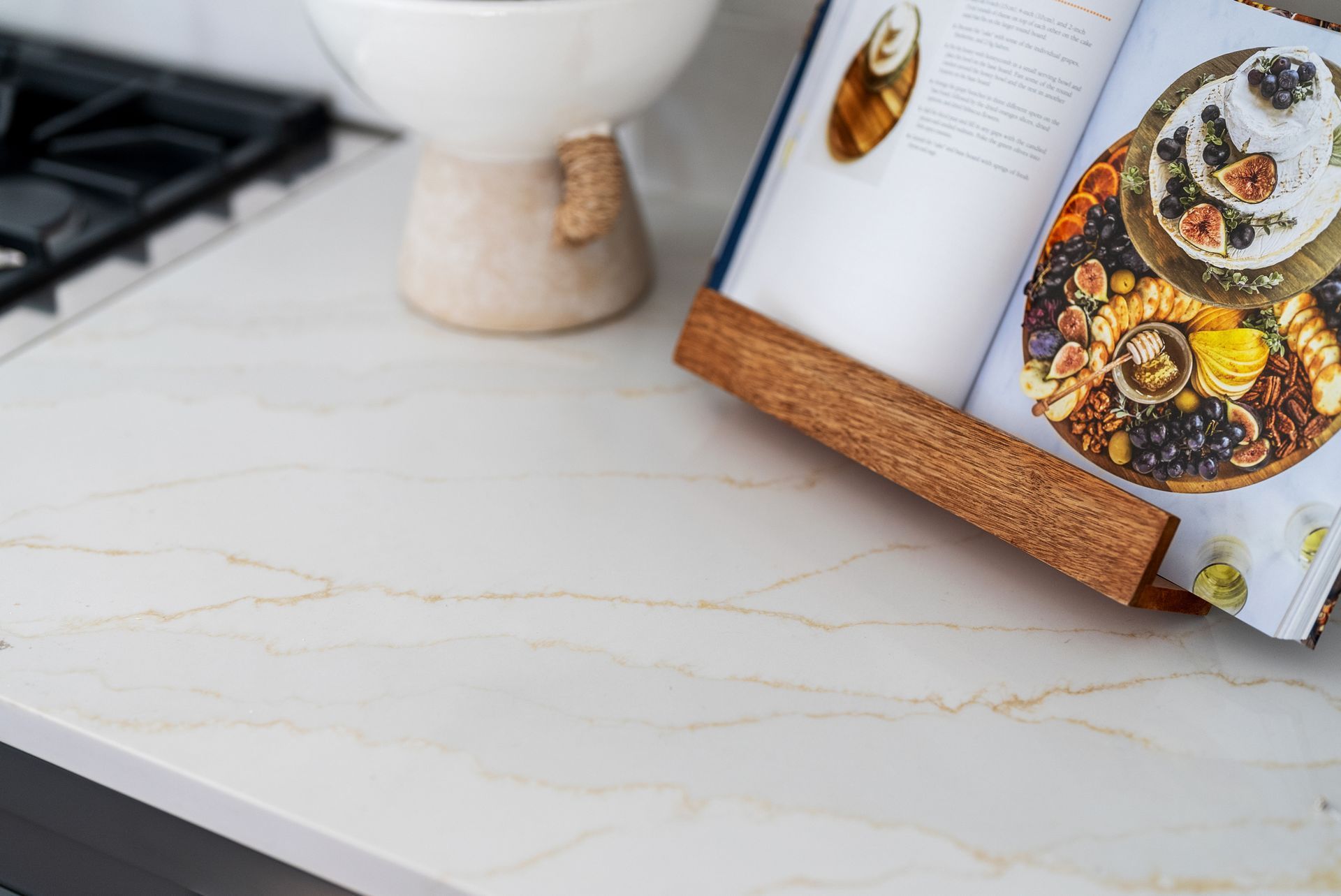 White countertop with cookbook open on wooden stand
