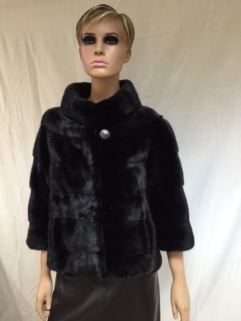 Black fur jacket on a mannequin, with a high collar and one large button.