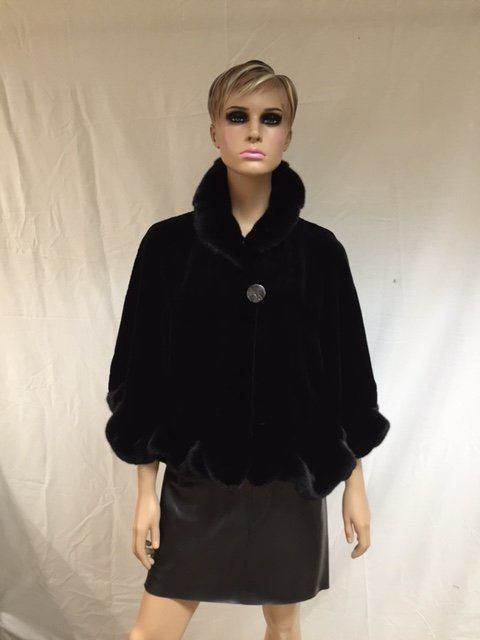 Black fur cape on a mannequin, with a high collar, button closure, and a black skirt.