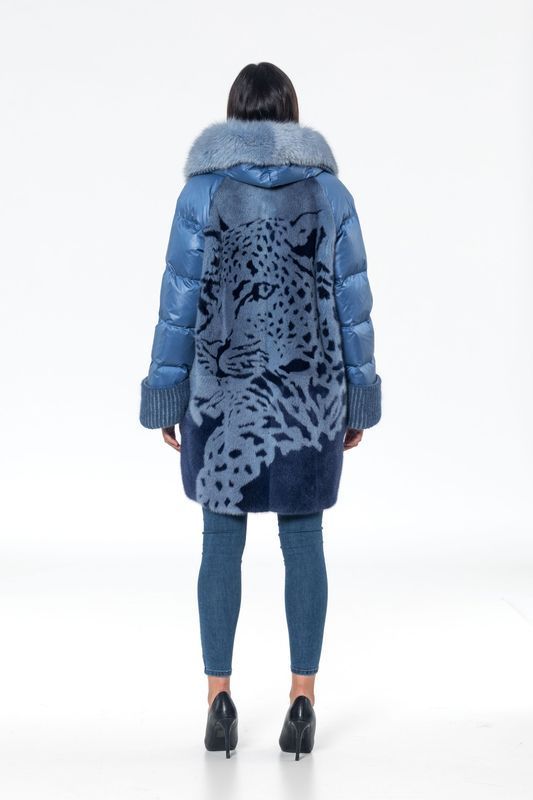 Woman wearing a blue puffer coat with a leopard design on the back, standing on white background.