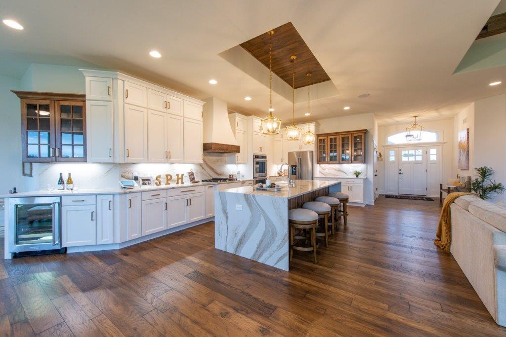A large kitchen with white cabinets and hardwood floors.