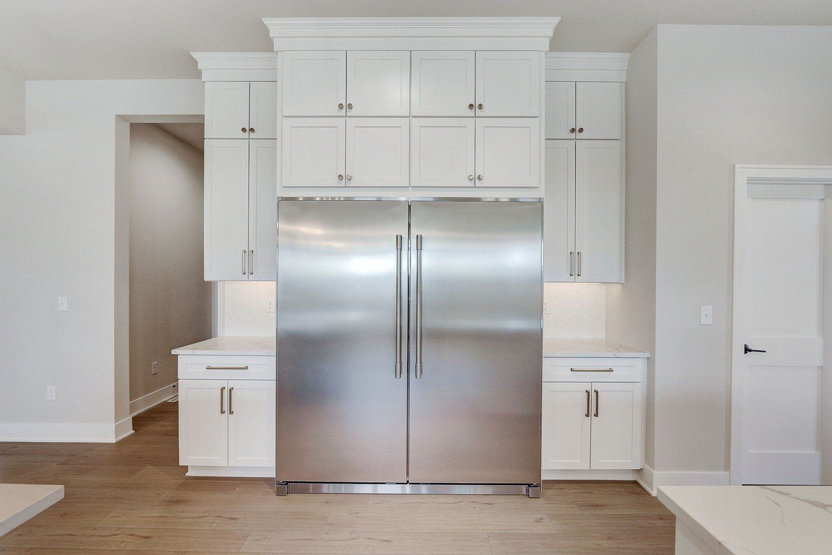 A kitchen with white cabinets and a stainless steel refrigerator.