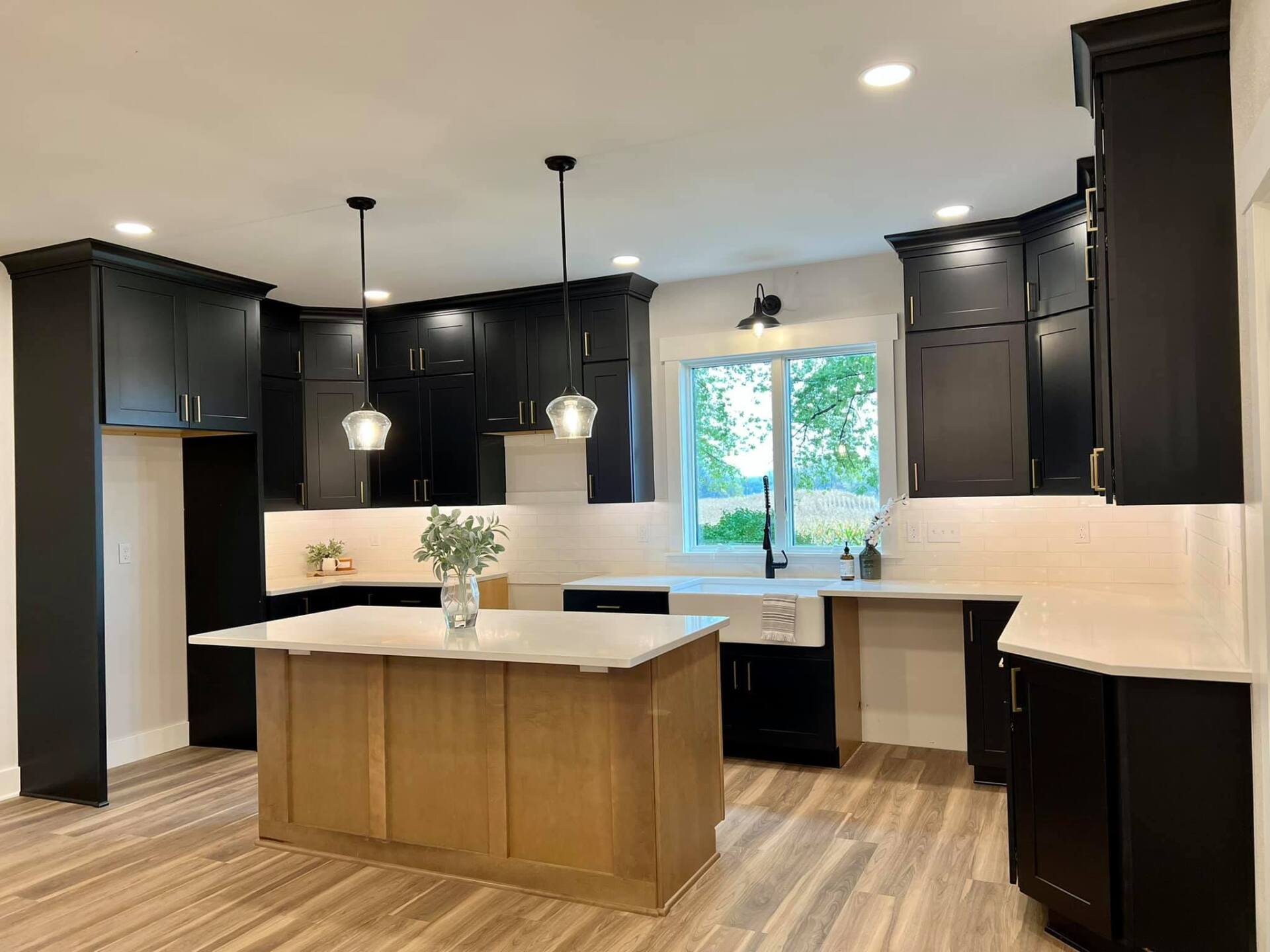 A kitchen with black cabinets and a large island in the middle.