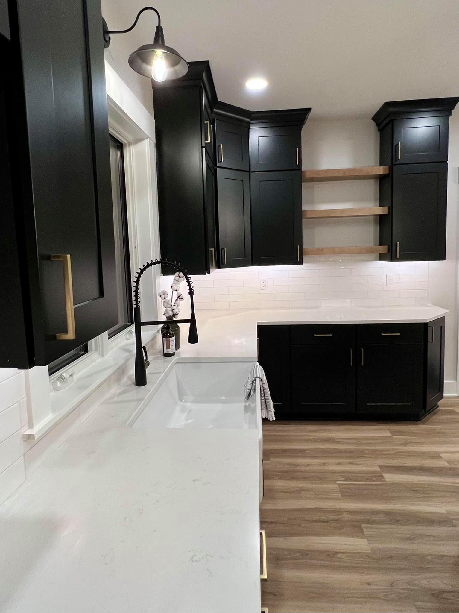 A kitchen with black cabinets , a sink , and a window.