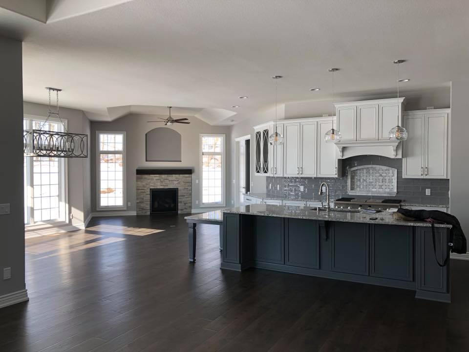 An empty kitchen with white cabinets and a large island.