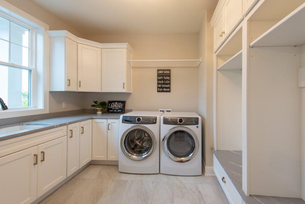 A laundry room with a washer and dryer and white cabinets.