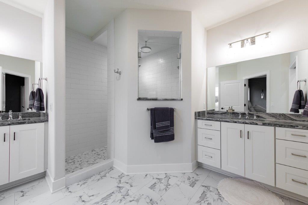 A bathroom with two sinks and a walk in shower.