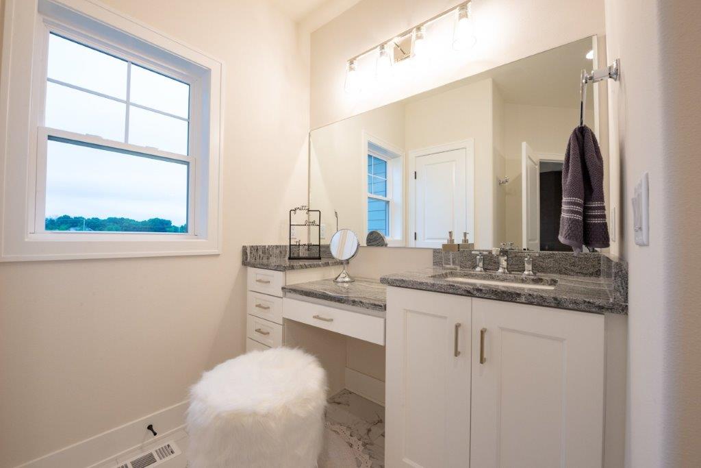 A bathroom with a toilet , sink , mirror and window.