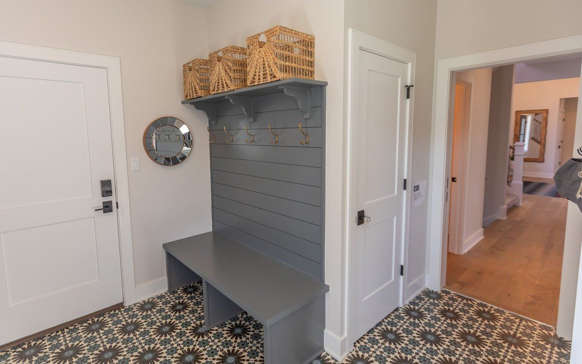 A hallway with a bench and a mirror in a house.