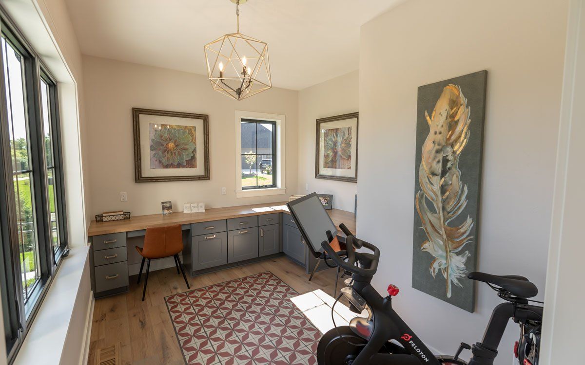A room with a bicycle and a desk in it.