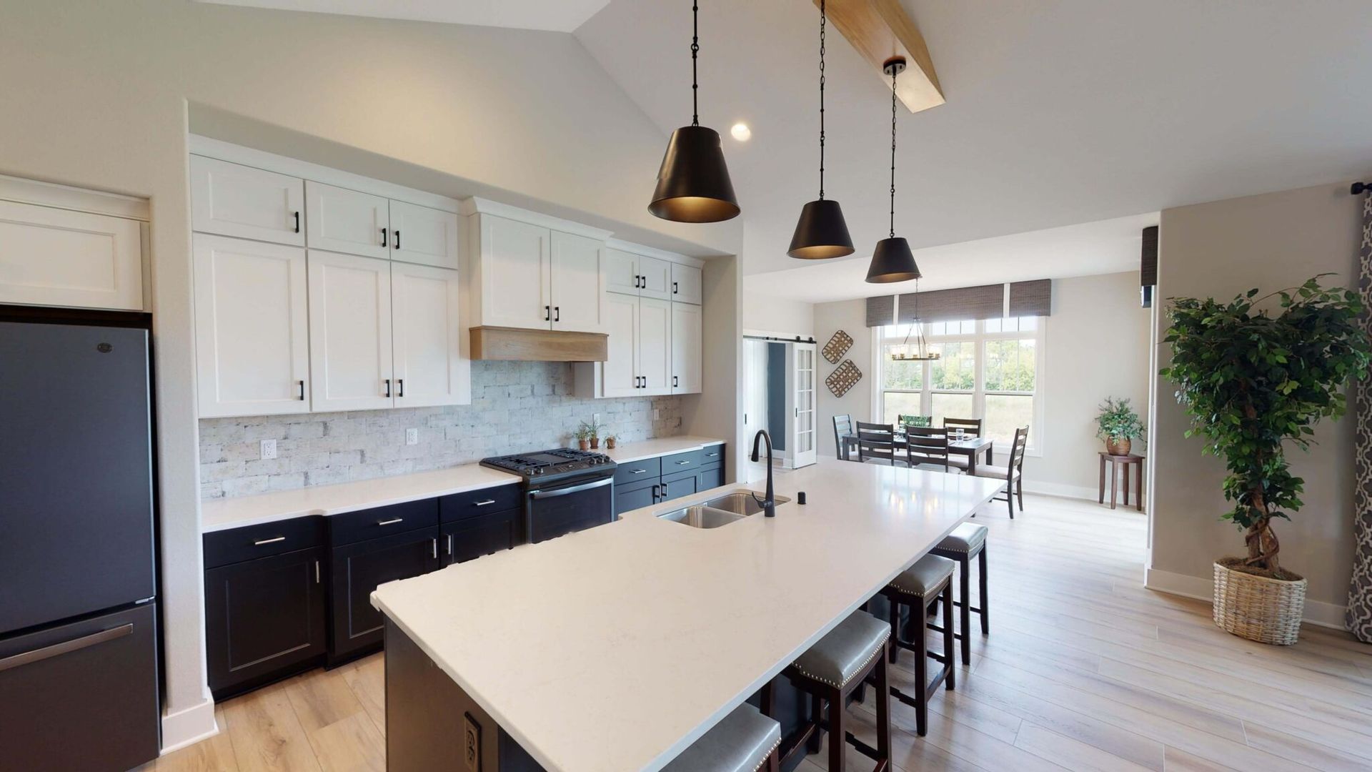 A kitchen with white cabinets and black appliances and a large island.