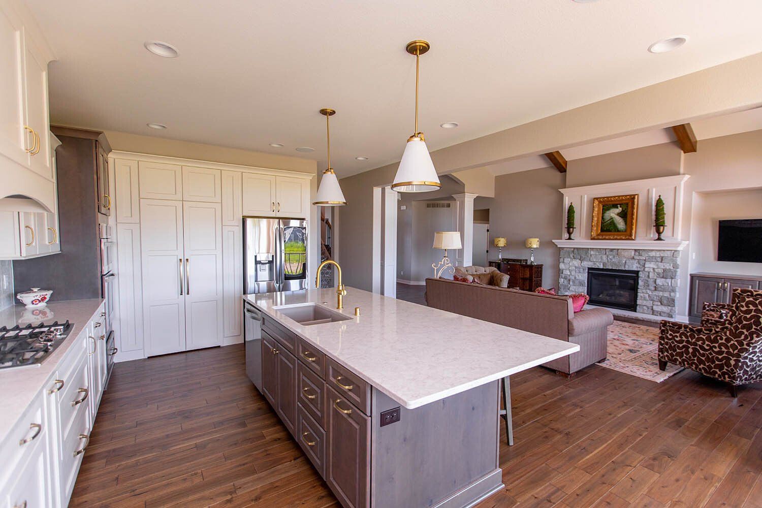 A kitchen with a large island in the middle and a living room in the background.