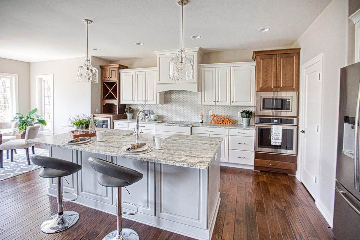 A kitchen with white cabinets , granite counter tops , stainless steel appliances and hardwood floors.