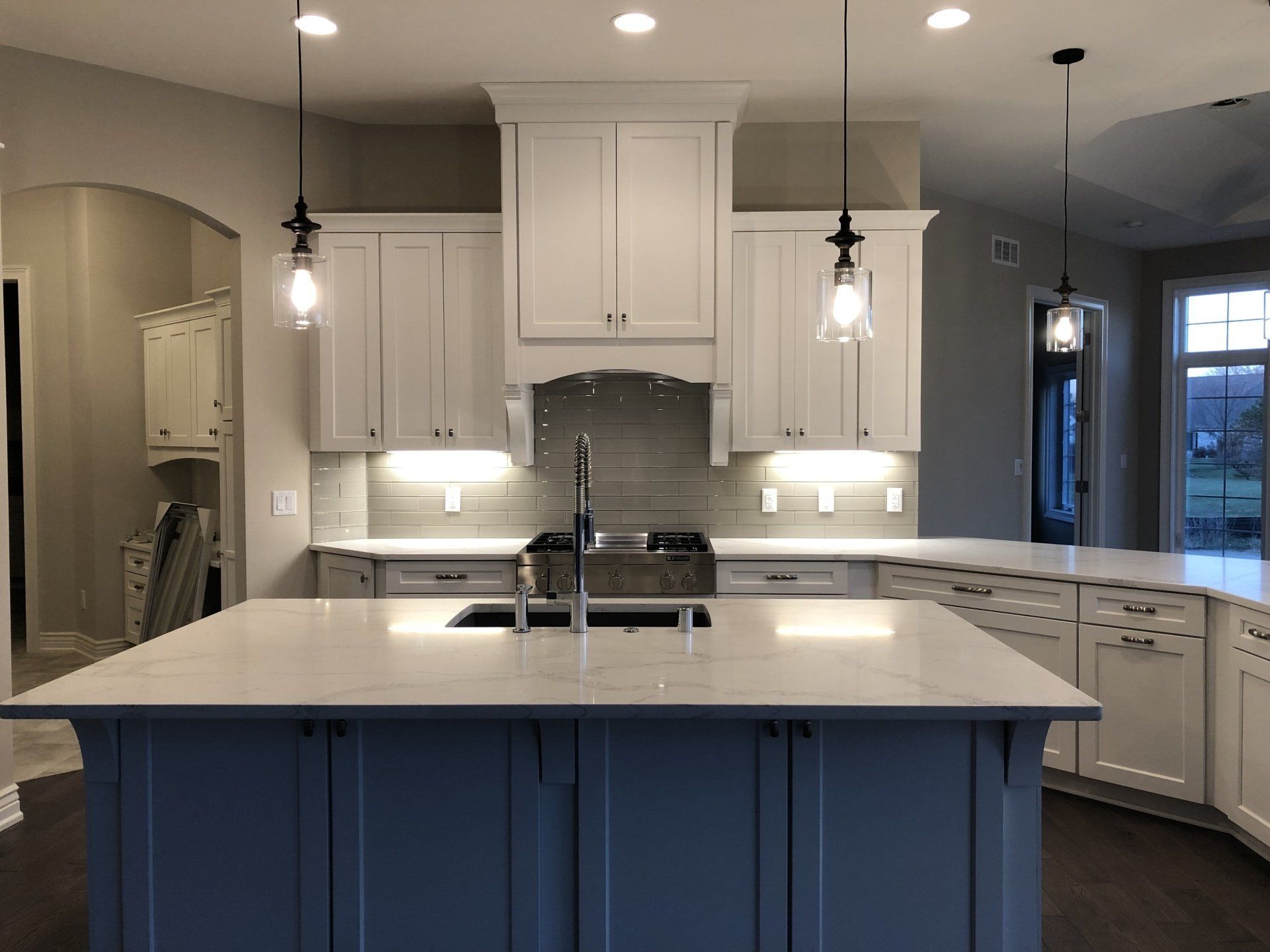 A kitchen with white cabinets and a large island in the middle.