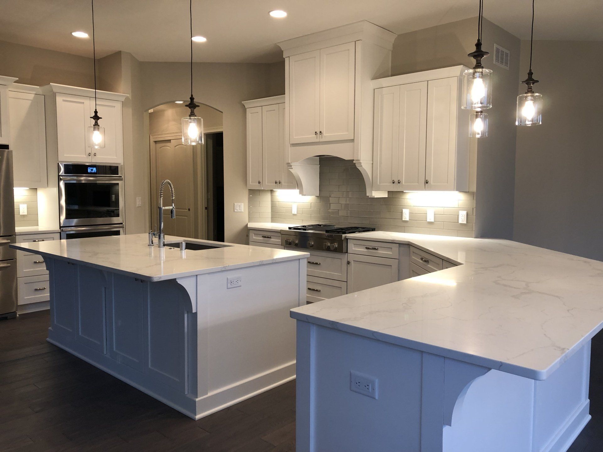A kitchen with white cabinets , granite counter tops , and stainless steel appliances.