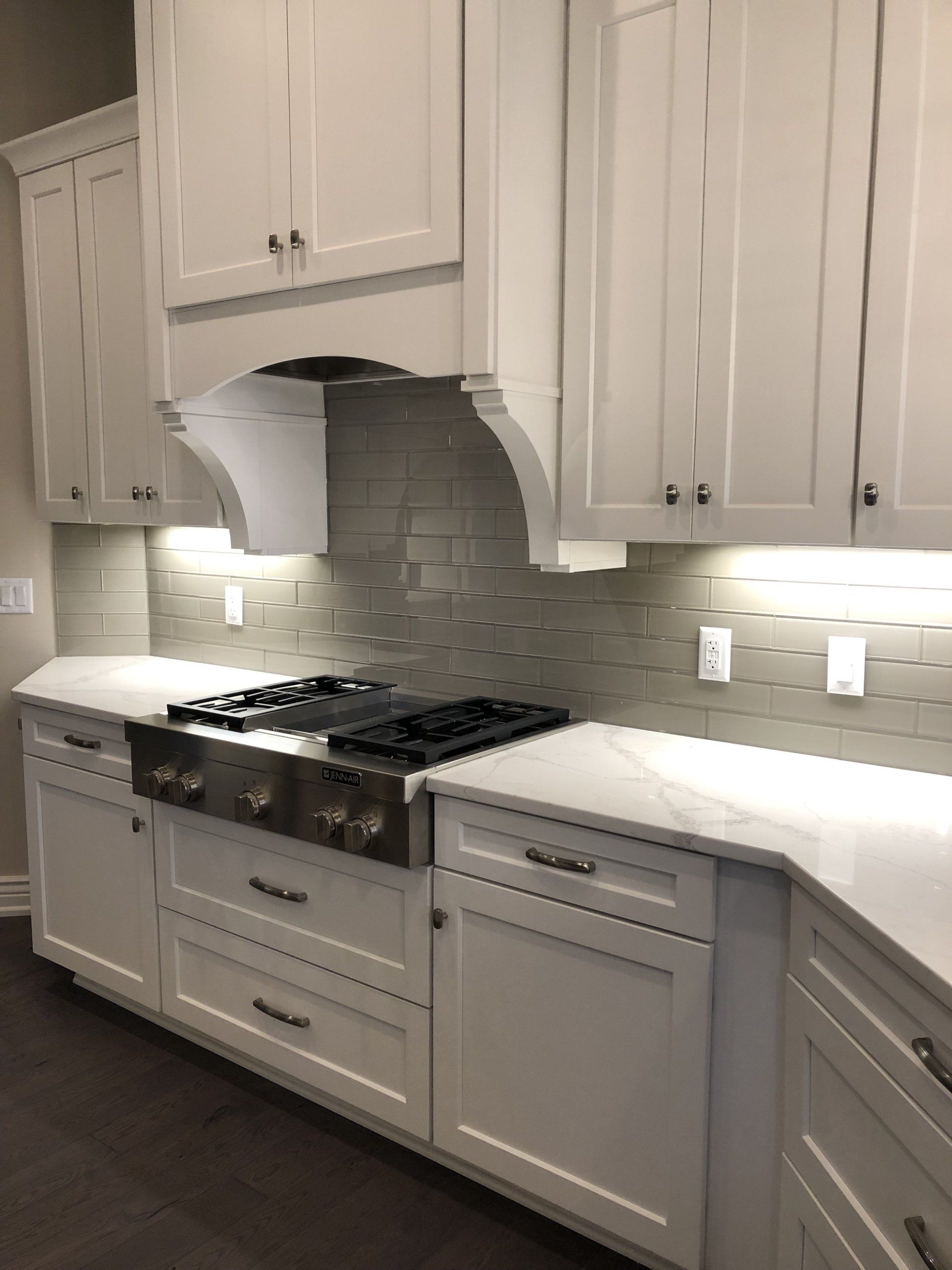 A kitchen with white cabinets and a stove top oven.