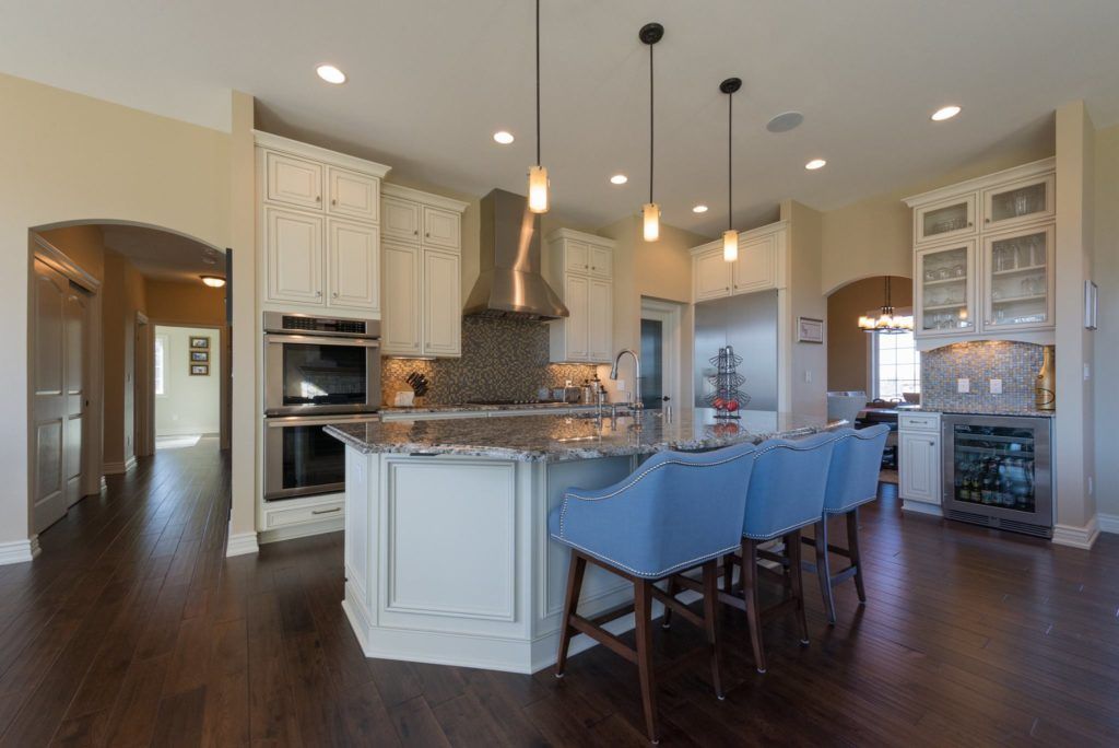 A large kitchen with a large island and blue chairs.
