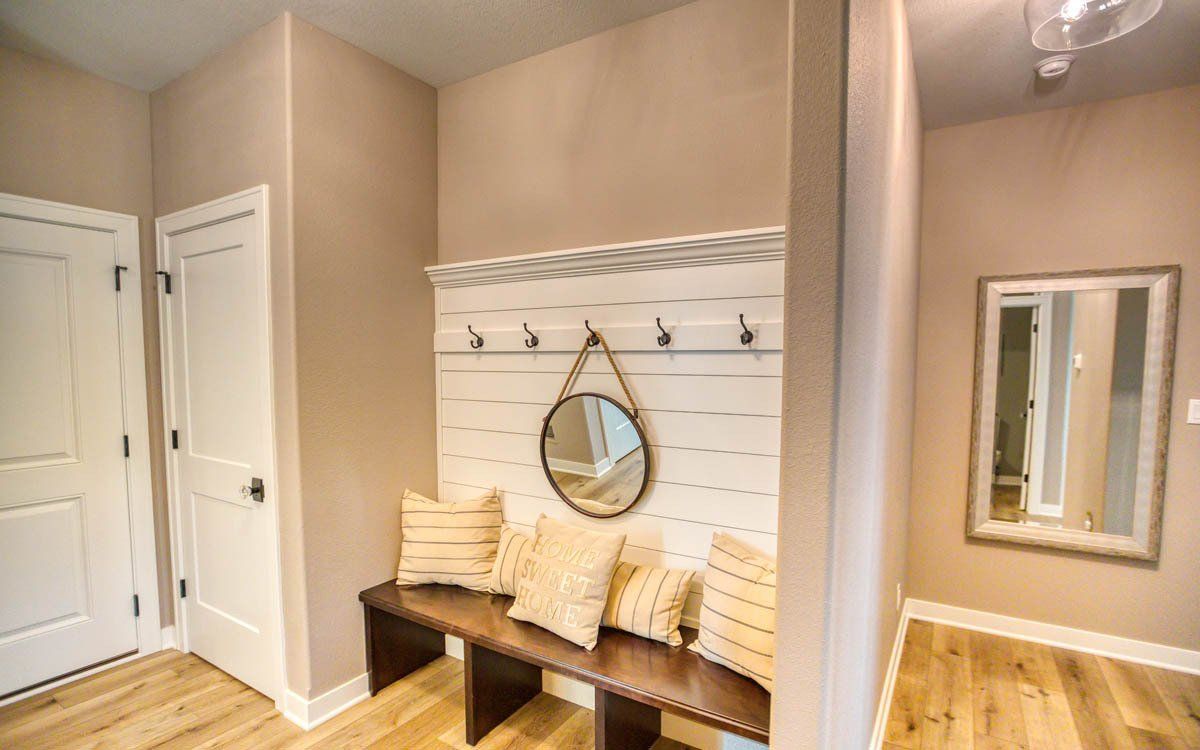 A hallway with a bench and a mirror on the wall.