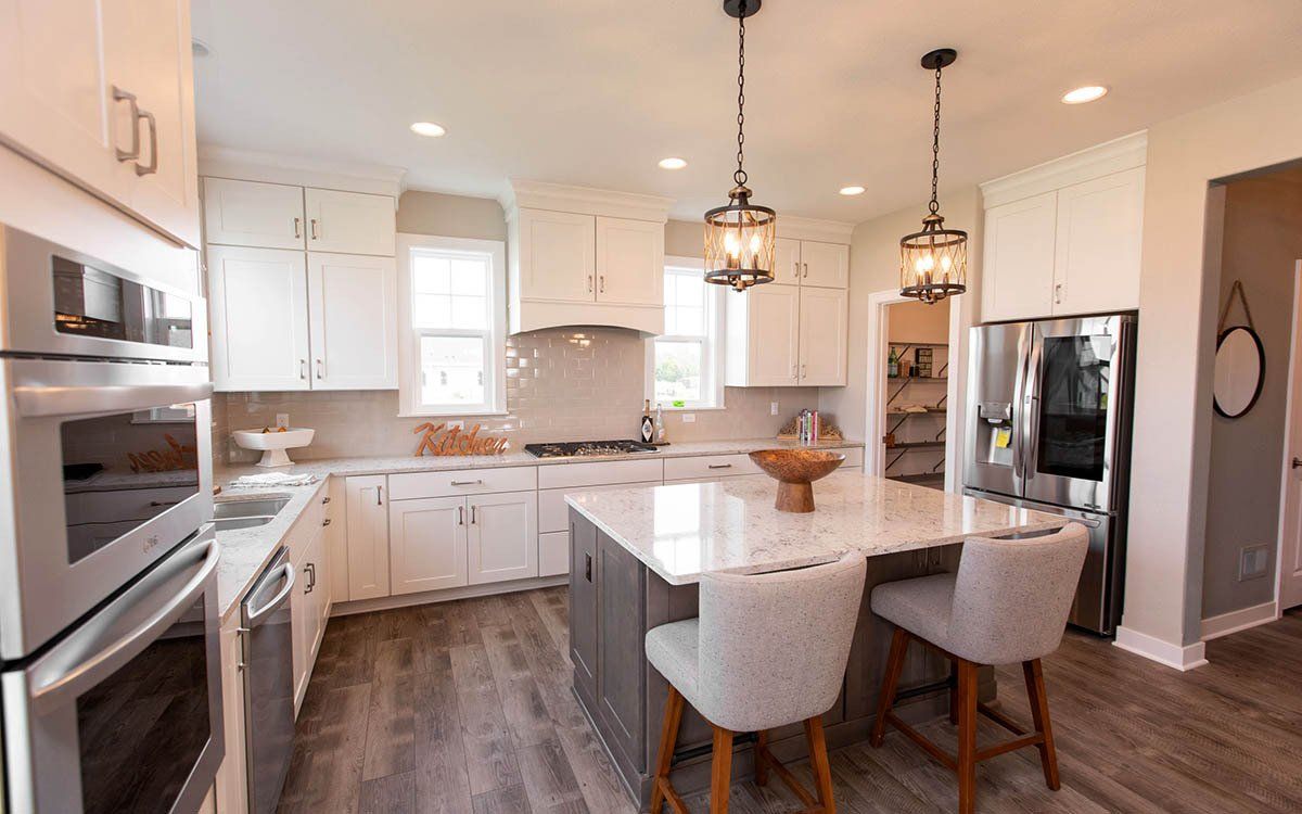 A kitchen with white cabinets , stainless steel appliances , and a large island.