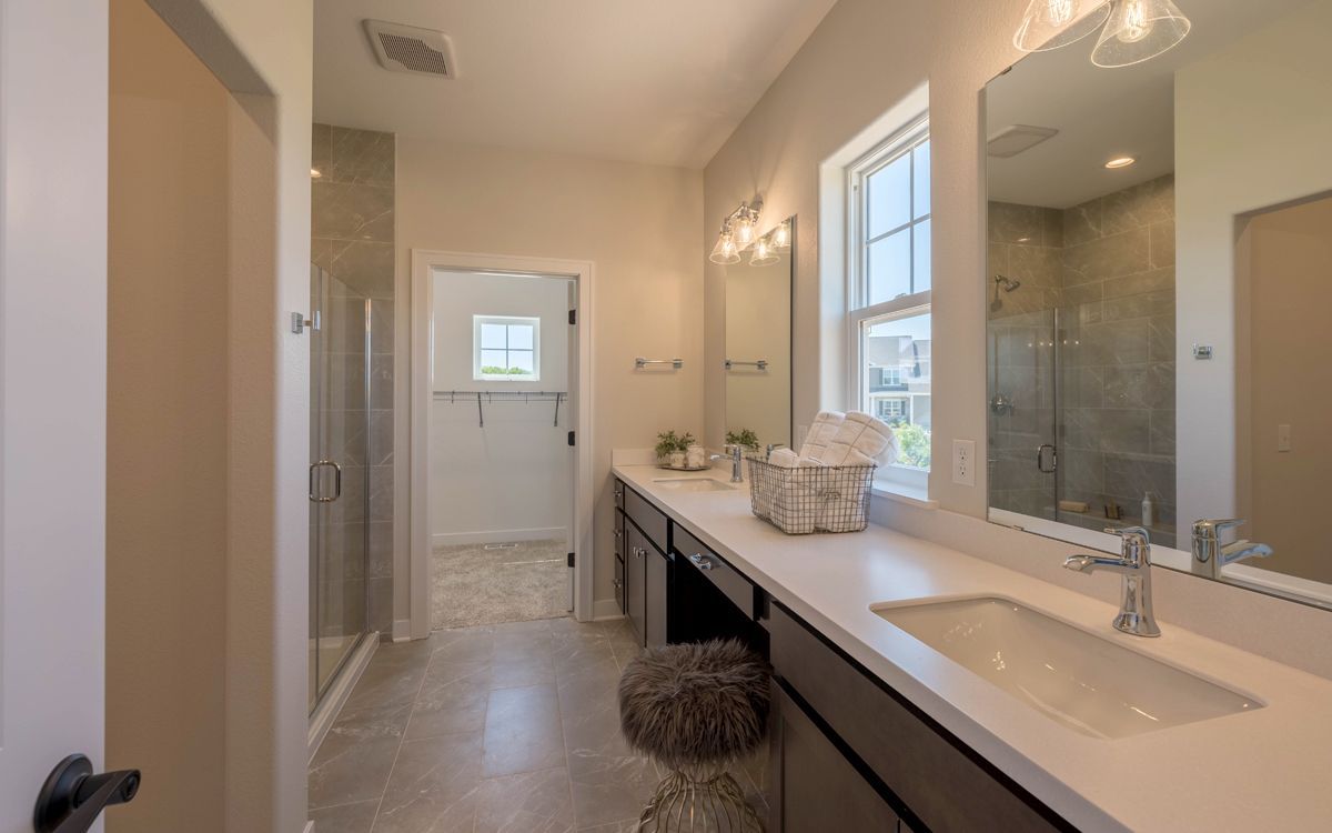 a bathroom with two sinks , two mirrors , and a walk in shower