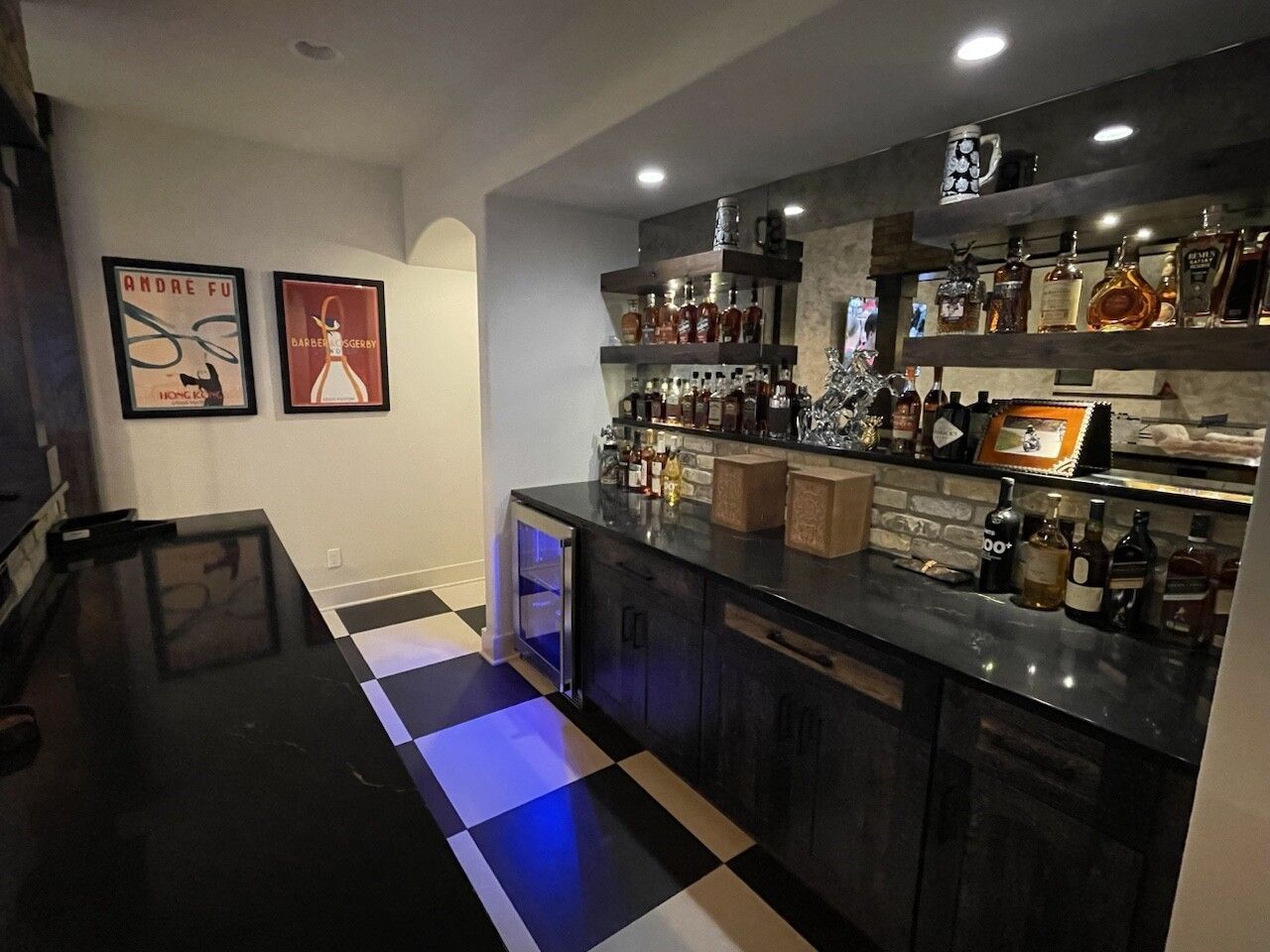 A kitchen with a lot of bottles of alcohol on shelves.