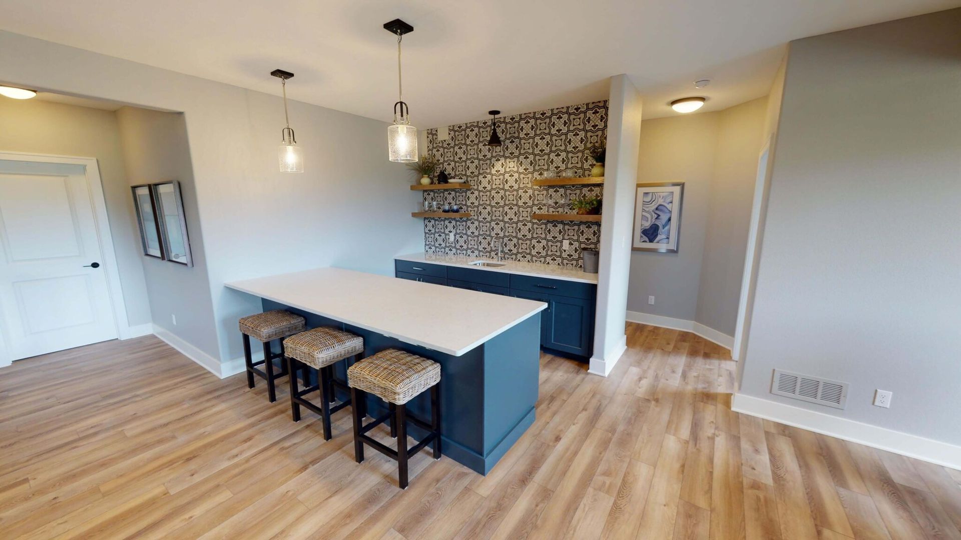 A kitchen with a large island and stools in it.