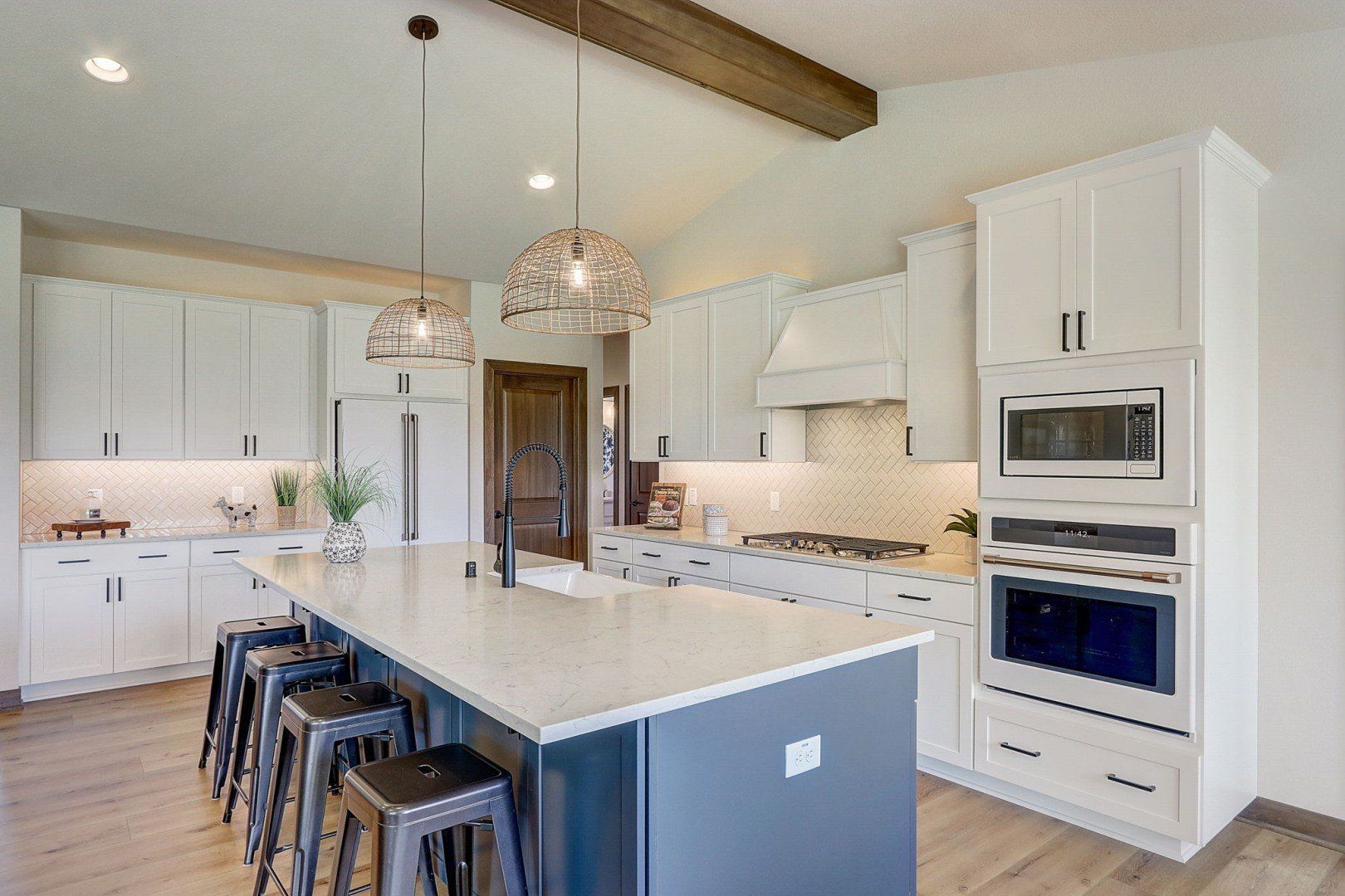 A kitchen with white cabinets, stainless steel appliances, and a large island.