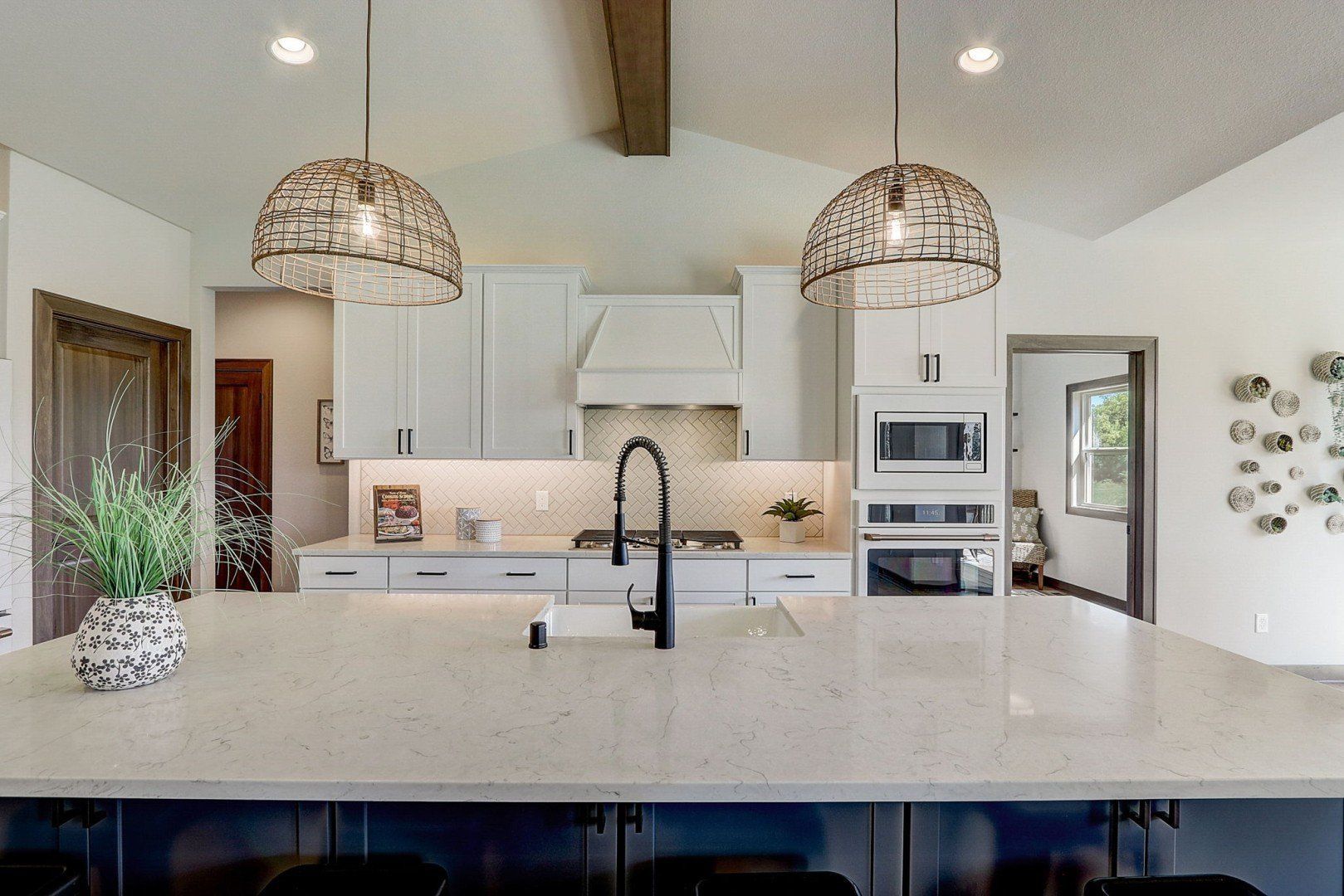 A kitchen with white cabinets, granite counter tops, stainless steel appliances and a large island.