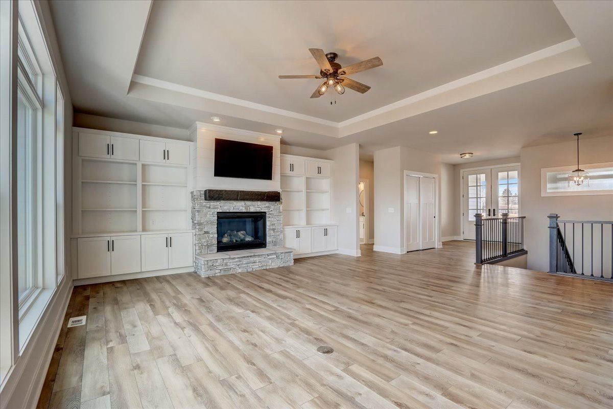 A living room with hardwood floors, a fireplace and a ceiling fan.