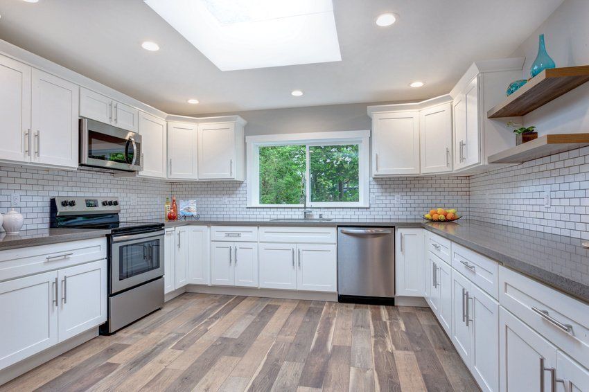 A kitchen with white cabinets , stainless steel appliances , and a skylight.