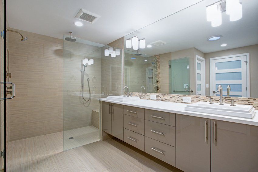 A bathroom with two sinks , a walk in shower and a large mirror.
