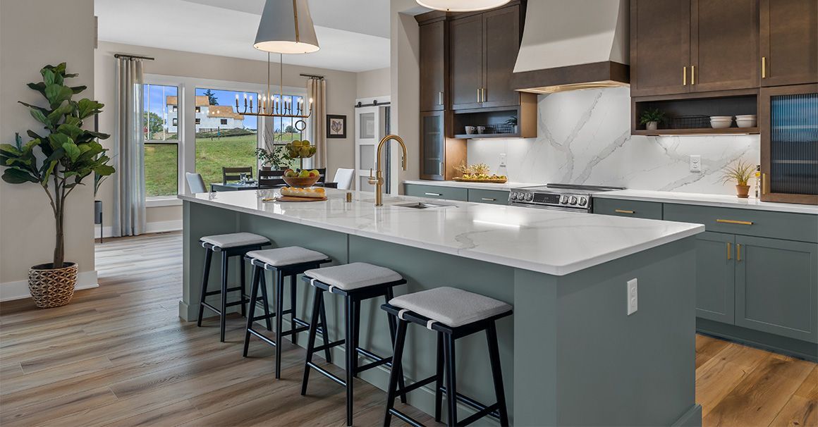A kitchen with a large island and stools in it.