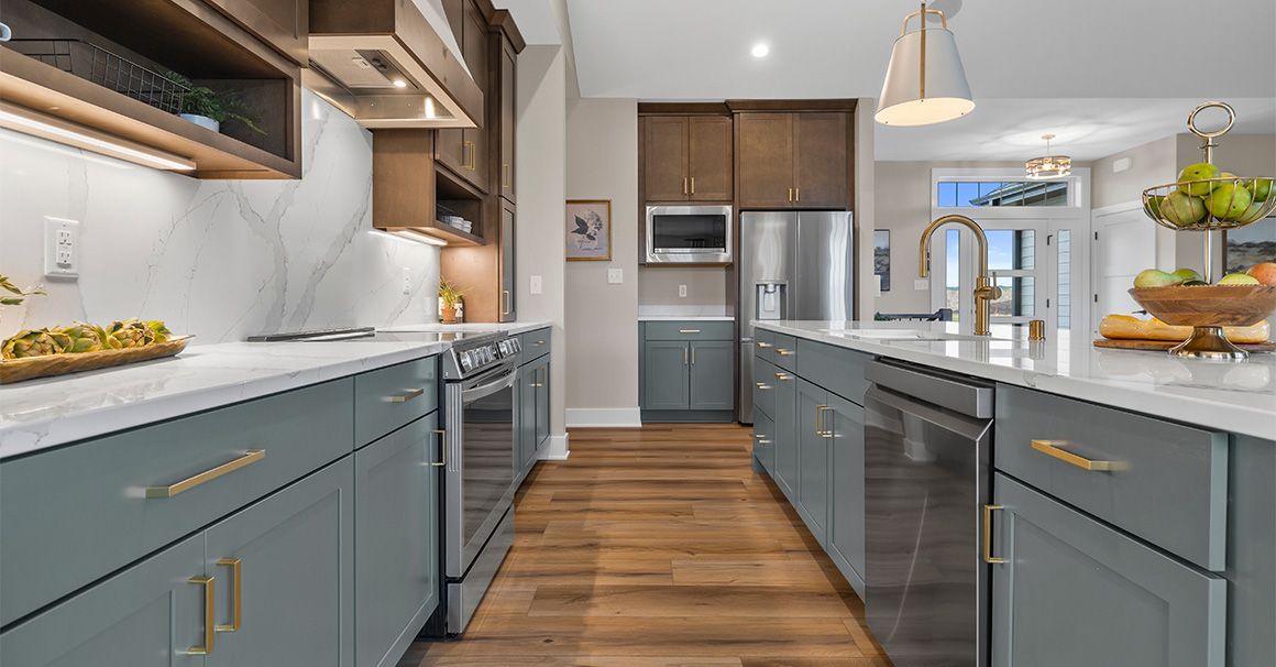 A kitchen with stainless steel appliances , gray cabinets , and wooden floors.