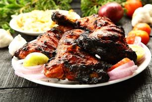 A white plate topped with grilled chicken and vegetables on a wooden table.