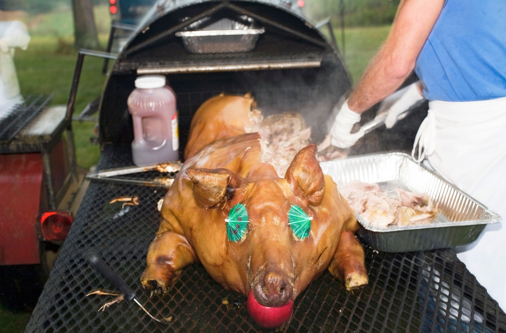 A pig with a red ball in its mouth is being cooked on a grill.