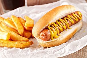 A hot dog with mustard on a bun and french fries.