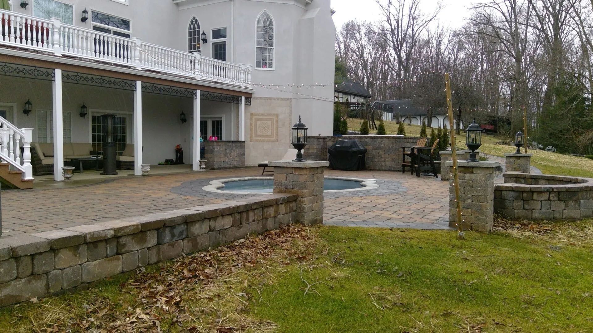 White house with porch and stone patio overlooking a grassy yard on an overcast day