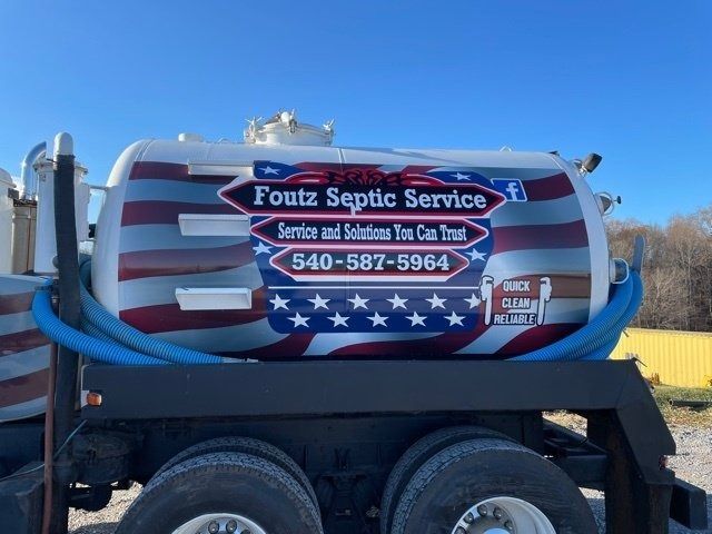 Foutz Septic Service truck with American flag tank and blue hose in a roadside lot