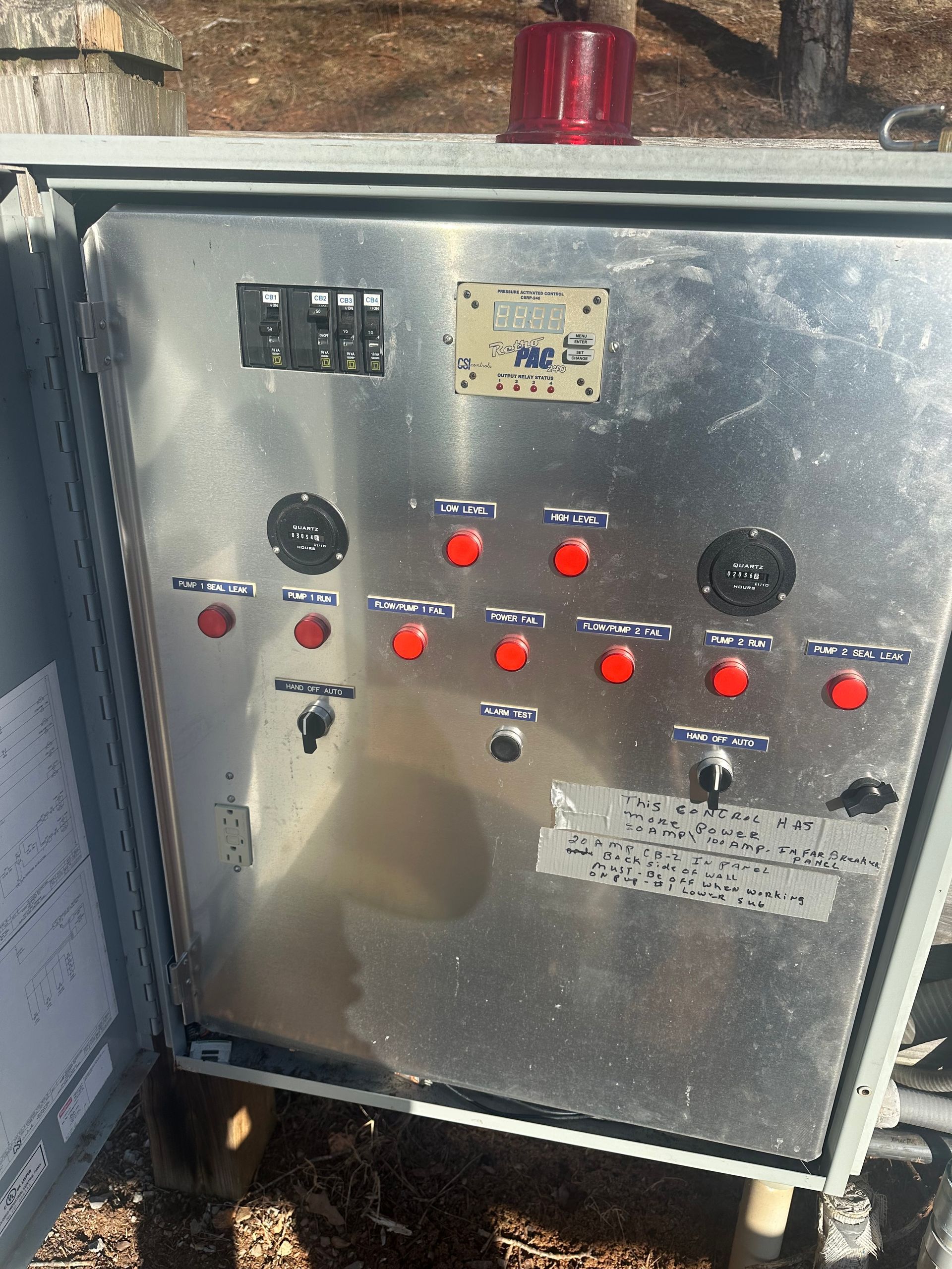 Open electrical control panel with red indicator lights inside a gray metal cabinet.