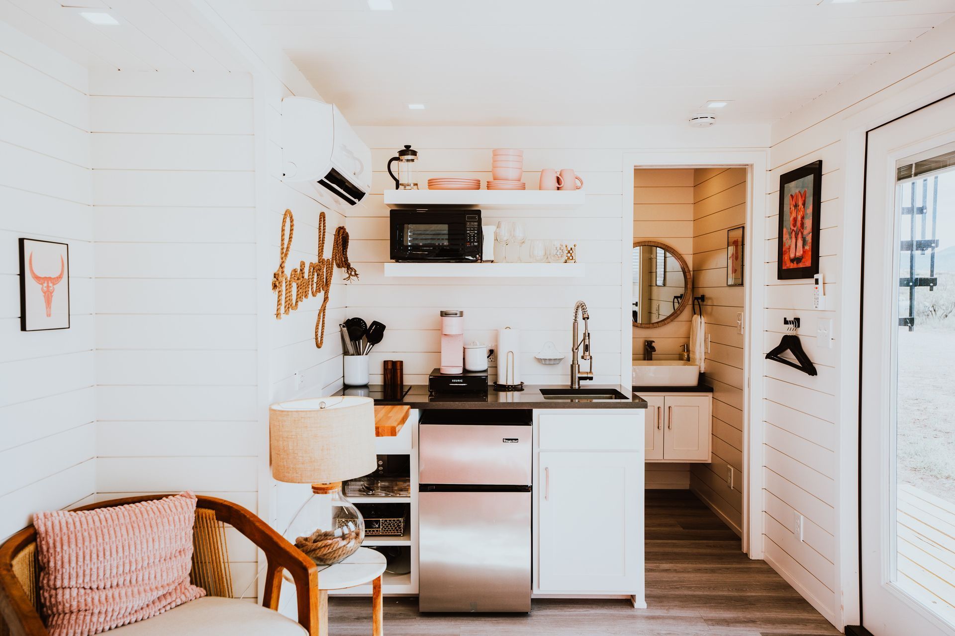 A small kitchen with stainless steel appliances and a chair.