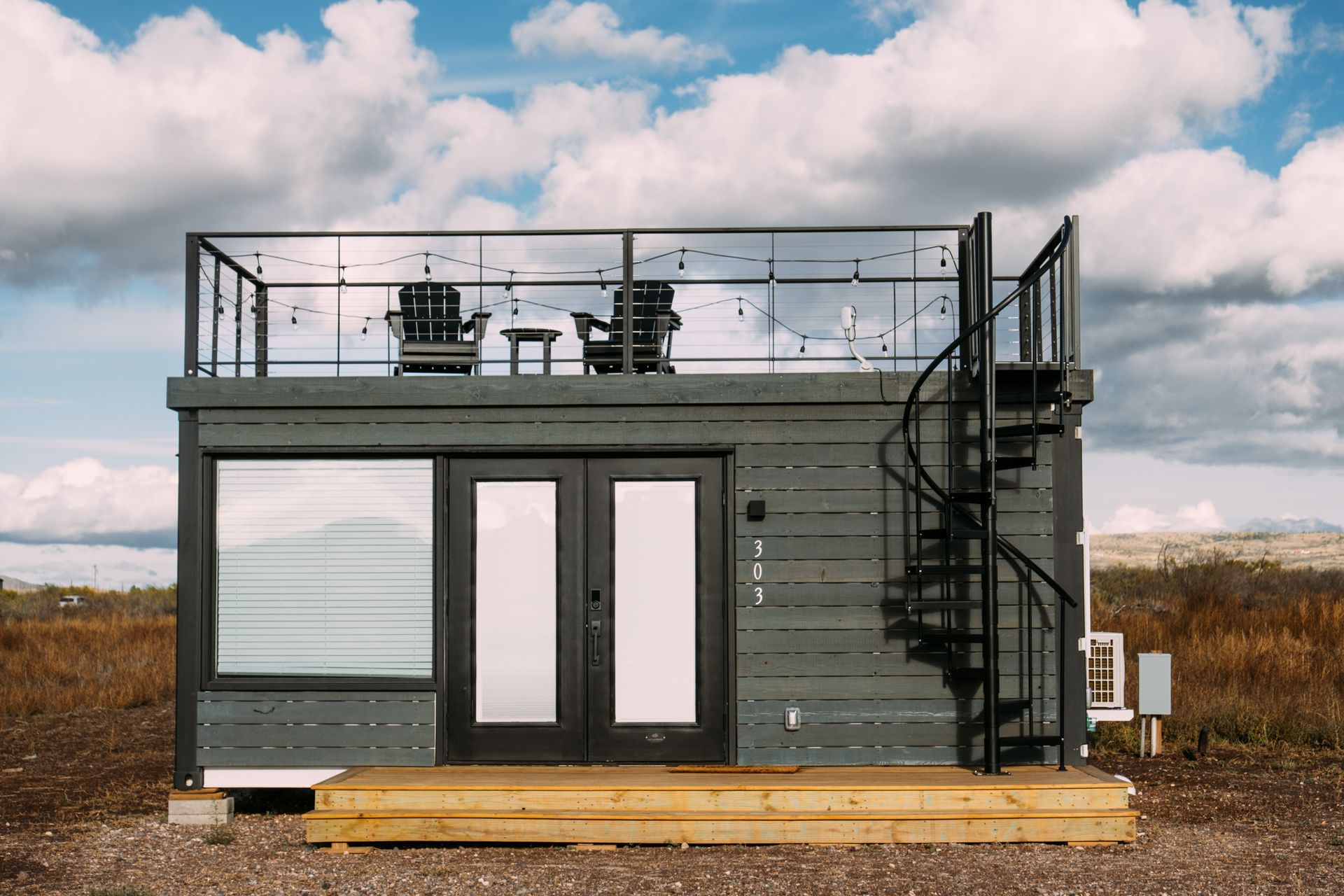 A small house with a balcony and stairs on top of it.