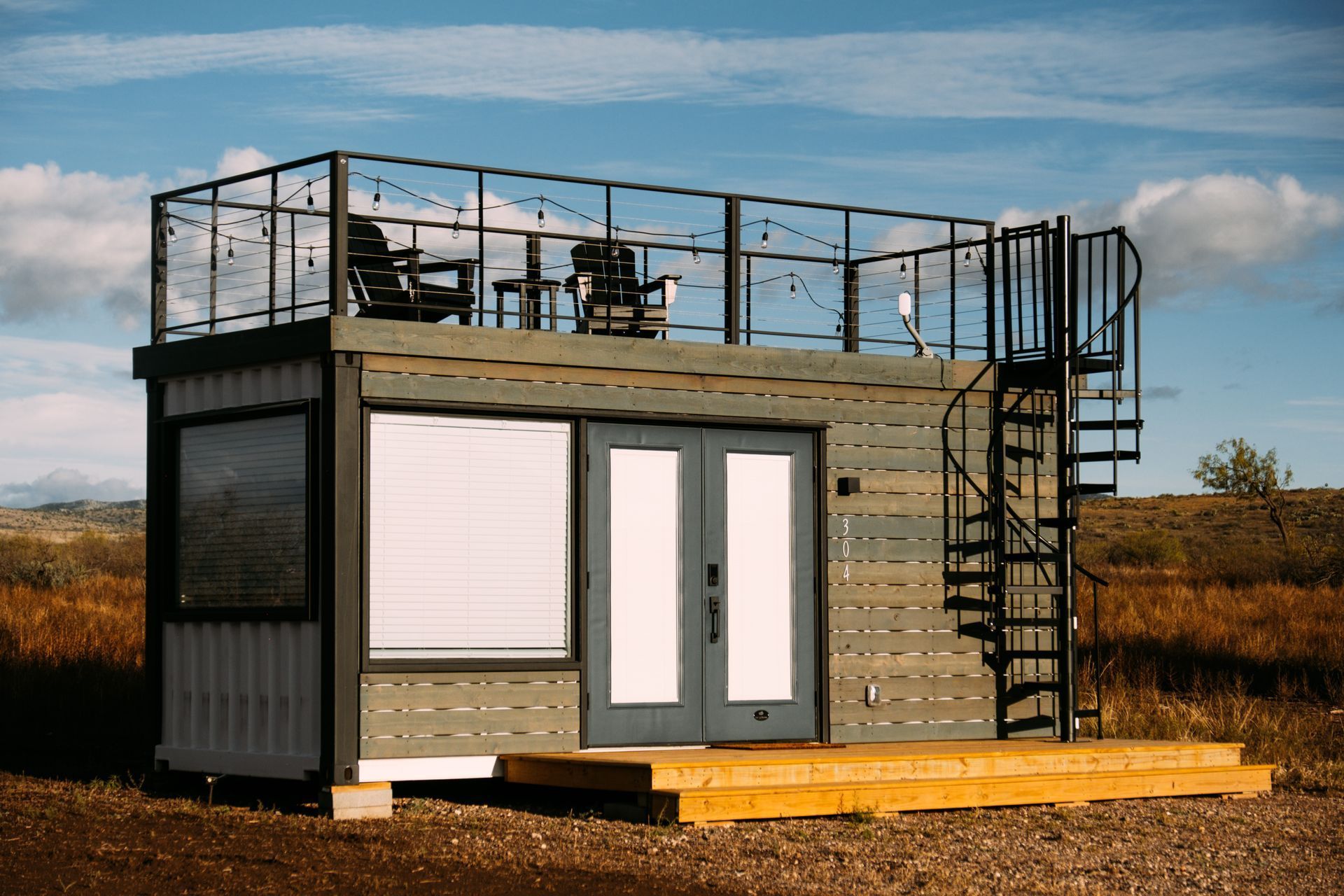 A small house with a balcony and stairs on top of it.