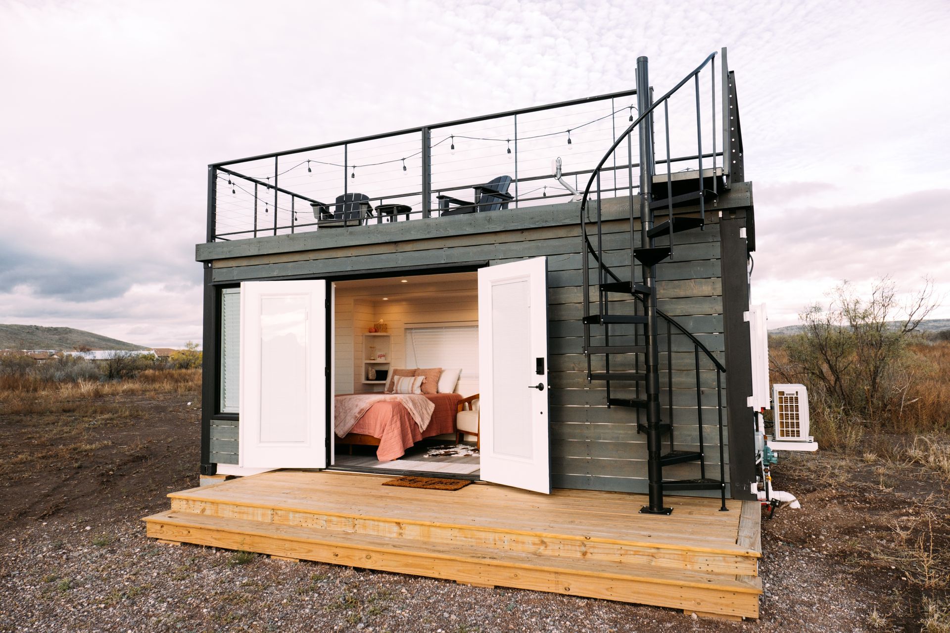 A small house with a spiral staircase and a balcony.