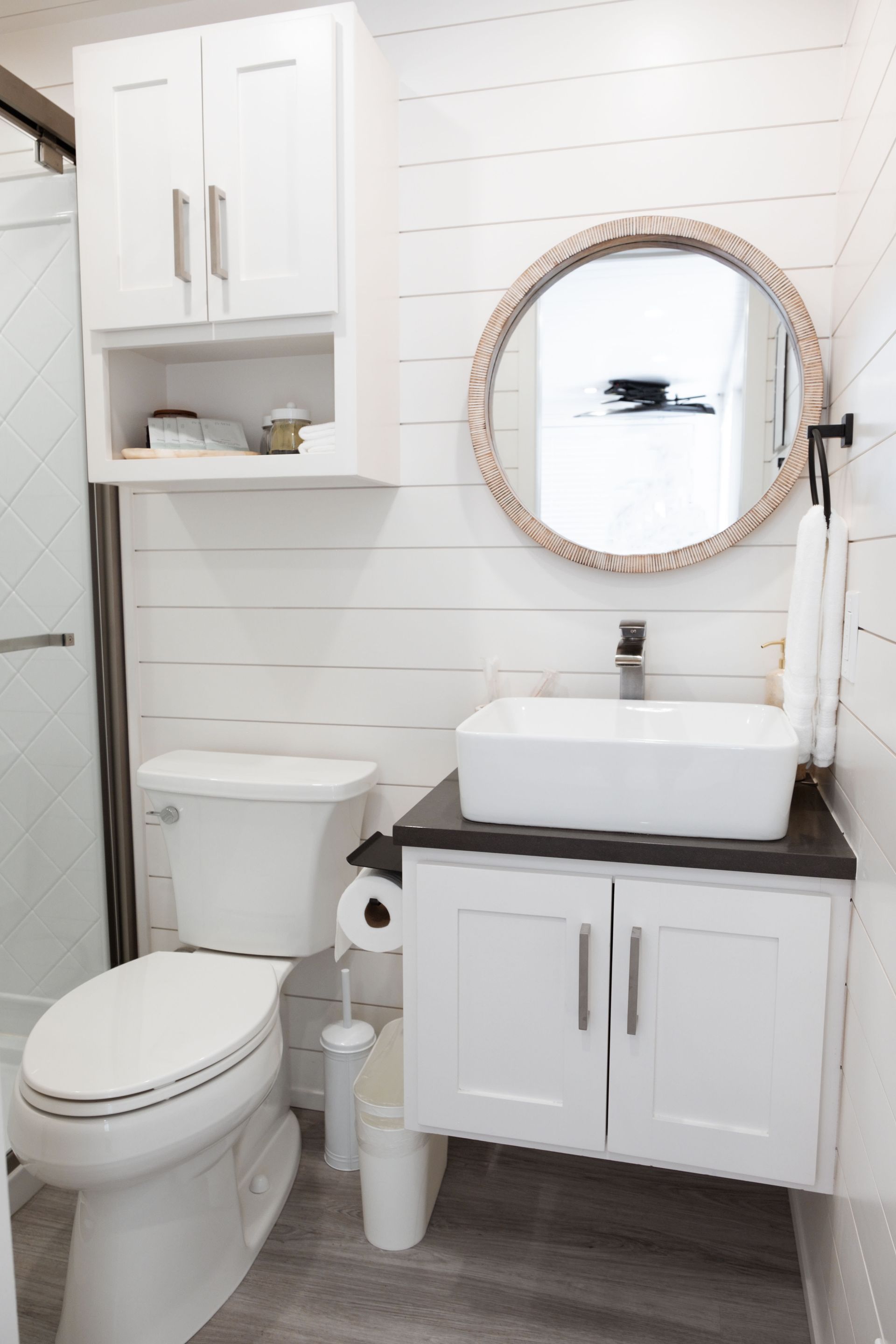 A bathroom with a toilet, sink, mirror and shower.