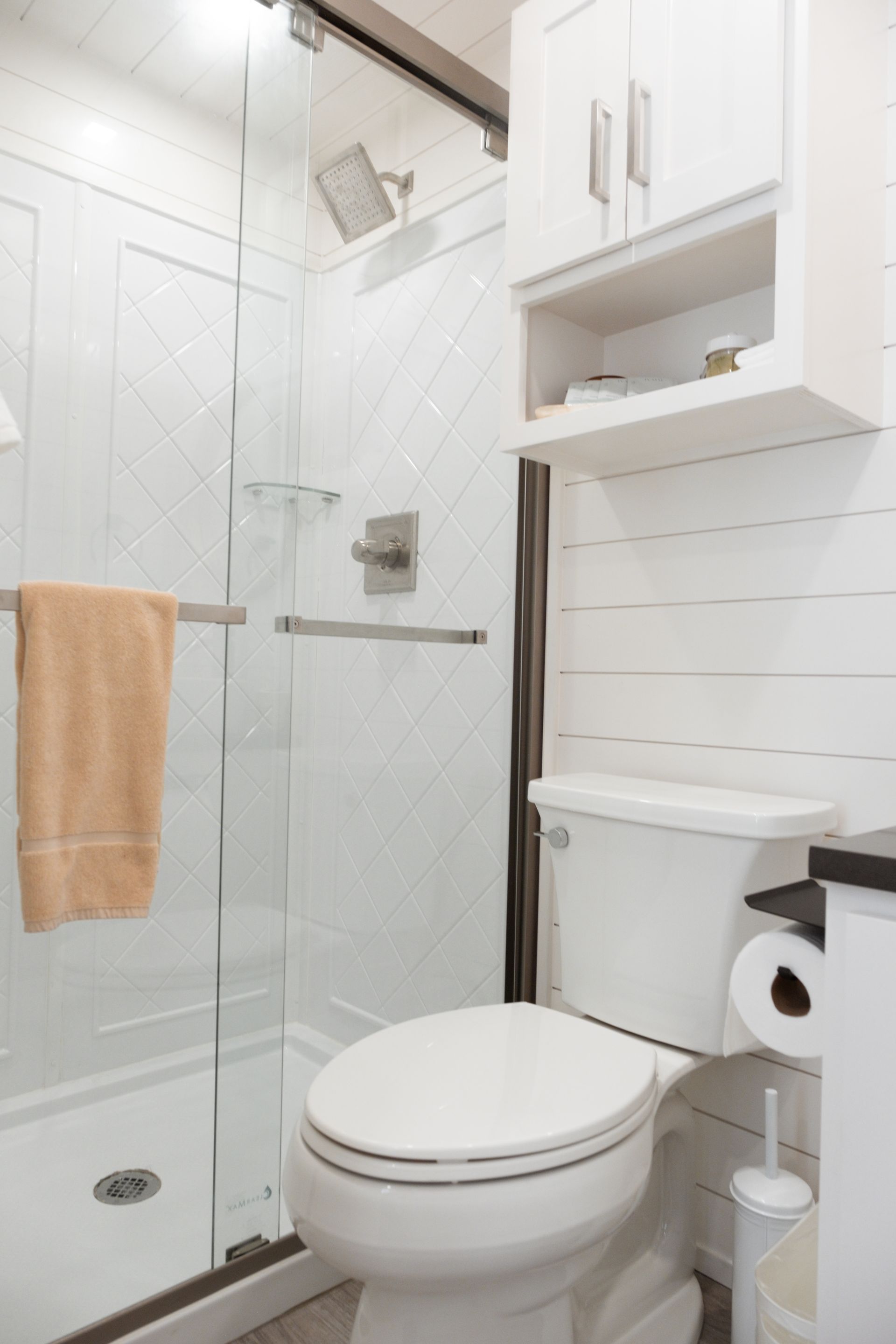 A bathroom with a toilet, shower, and towel rack.