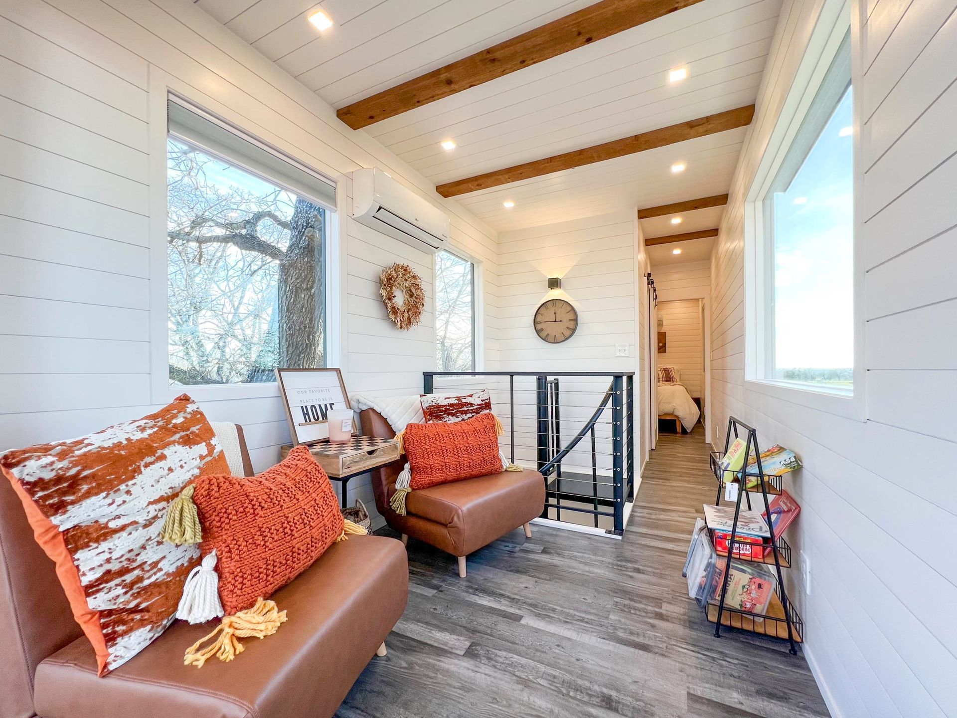 A living room with a couch and two chairs and a clock on the wall.