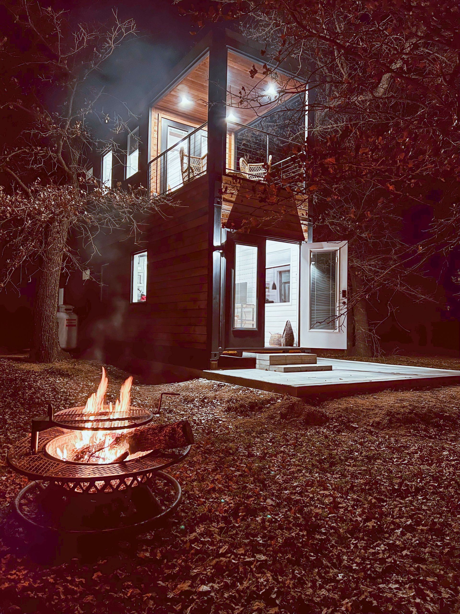 A fire pit is in front of a house at night.