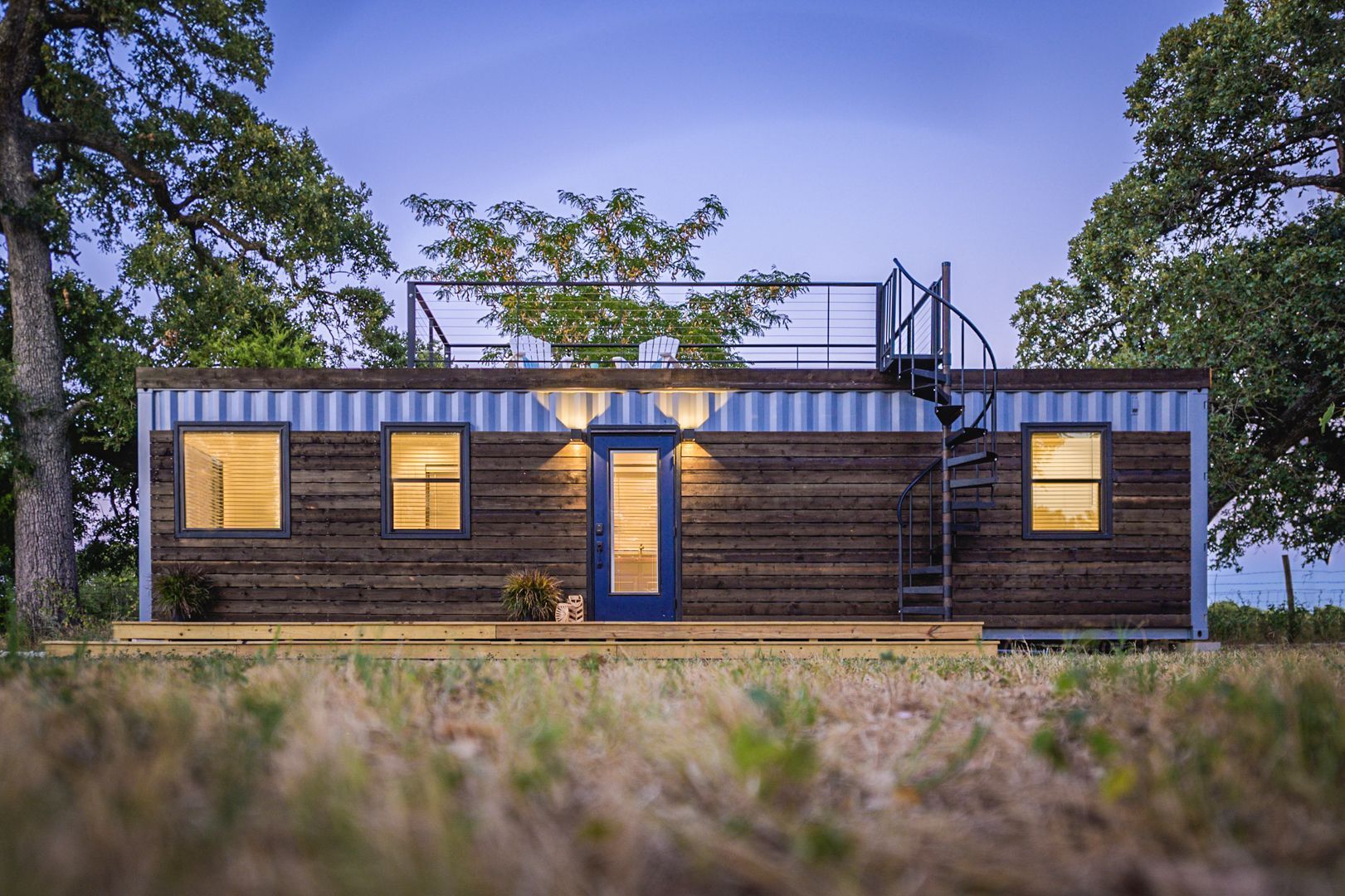 a small house with a spiral staircase on the roof is sitting in the middle of a field