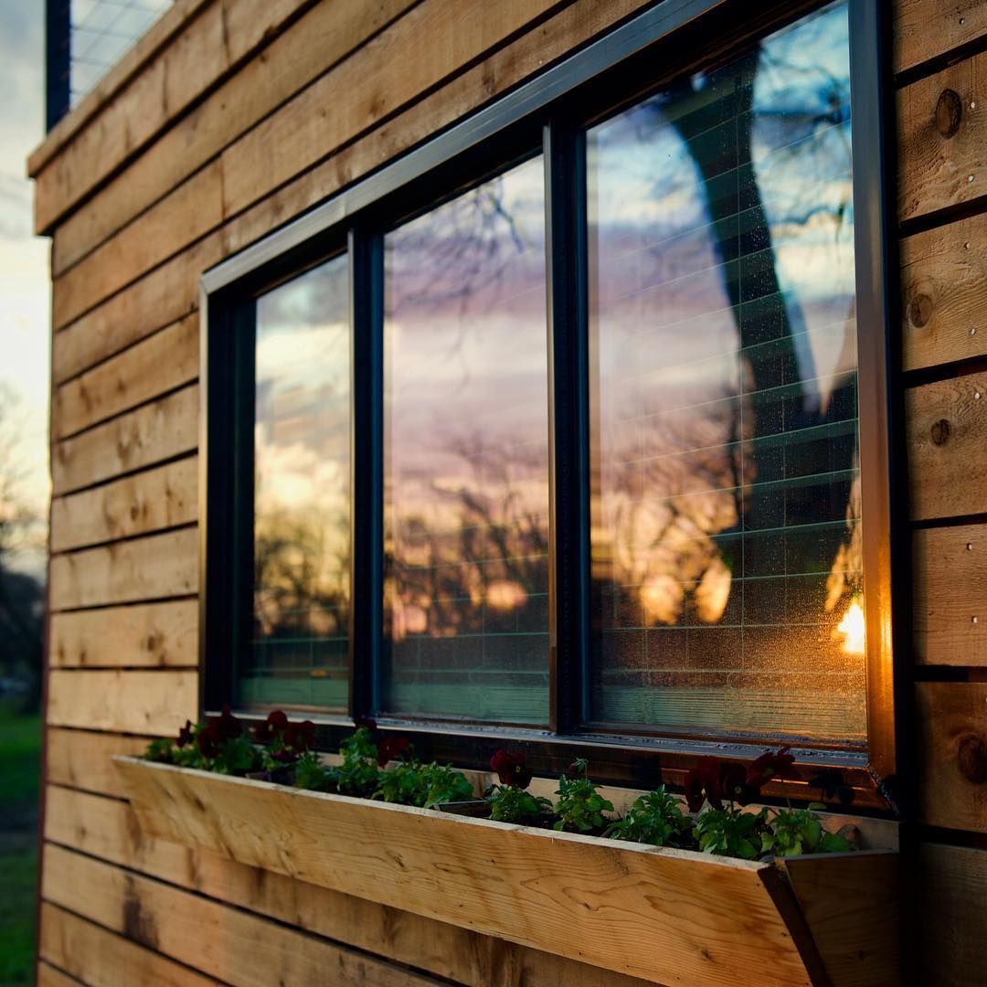 A wooden building with a window with a planter in front of it.